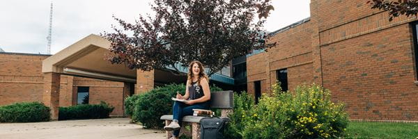 Student sitting on bench outside Brooks Campus