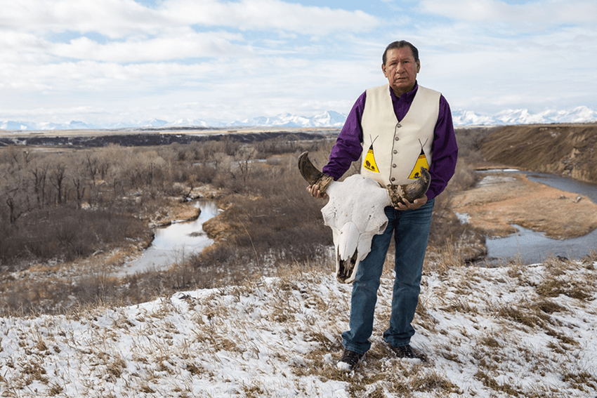 Elder Dan Fox stands near the Belly River holding a bison skull