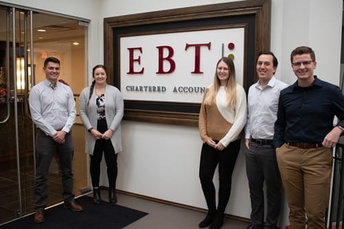 Medicine Hat College alumni standing by Chartered Professional Accountants office sign