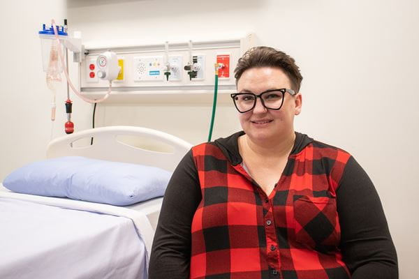Health Care Aide Alumni, Jennifer Kuipers, sitting in the medical simulation lab. 