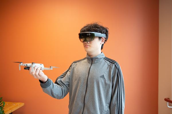 Student holds a drone in his hand while wearing virtual reality goggles