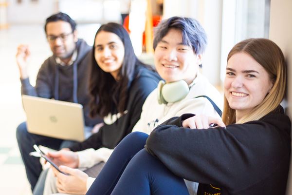 Four students sitting on bench in hallway