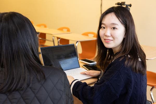 Student typing on laptop looking over left shoulder