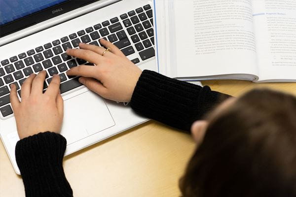 Close up of student typing on a laptop