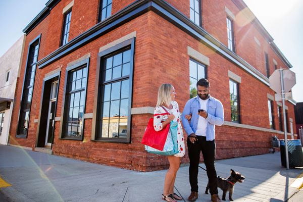 Two people standing with a dog in downtown Brooks, Alberta