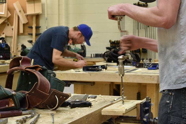 Carpentry students working with tools in the lab