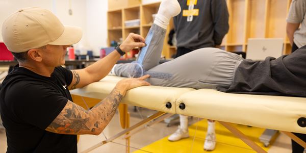 Student performing a knee assessment on classmate laying on massage table
