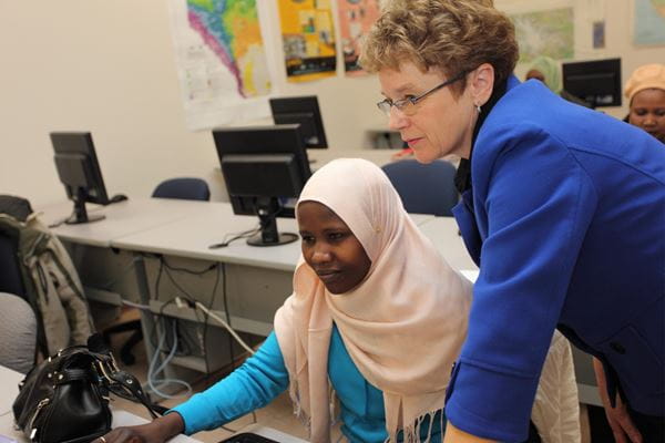 An instructor assisting a student with their work in a computer lab