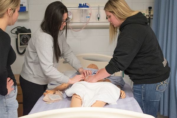 Nursing students practicing on simulation mannequin