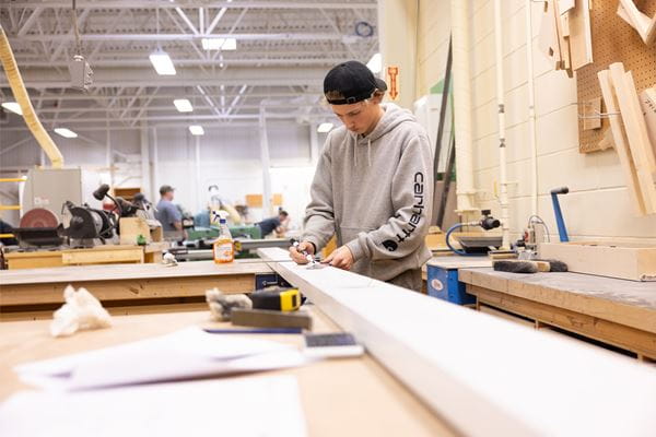 Person measuring and marking woodwork.