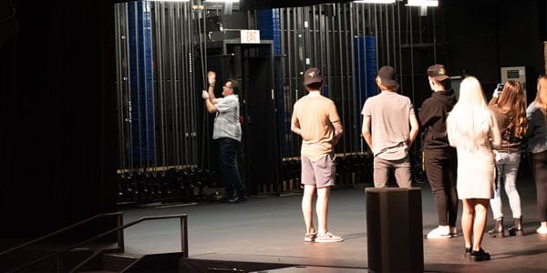 Group of students watching a demonstration backstage in a theatre