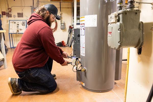 Person using tools to fix water heater. 