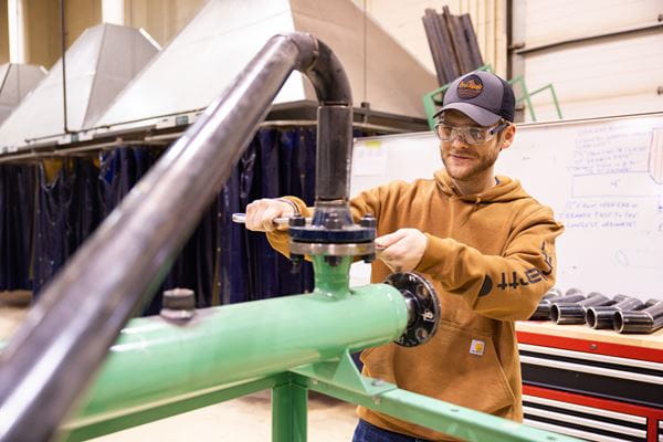 Person using a tool to fix a pipe. 