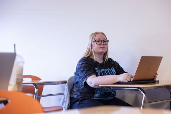 Student working with laptop in classroom.