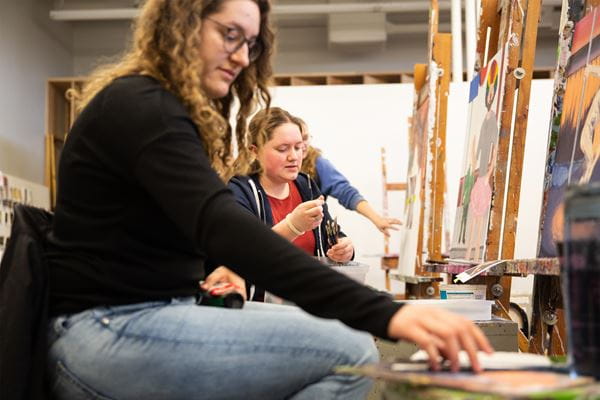 Students creating art and painting on easles