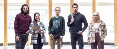 Five students standing in indigenous gathering space