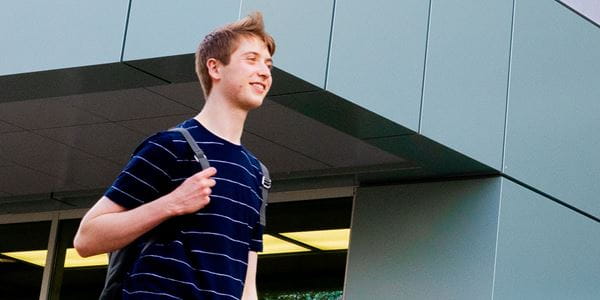 Student with backpack walking outside library