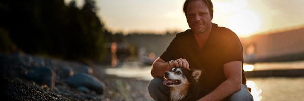 Brandon Niwa kneeling with his dog. 