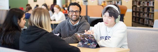 Four students sitting at work table in Vera Bracken Library