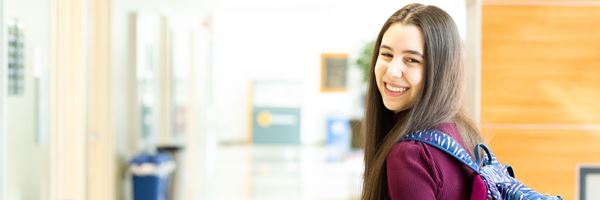 Student standing with a backpack in hallway,