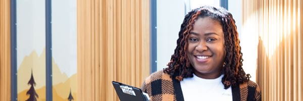 Student holding books, leaning against a wall.