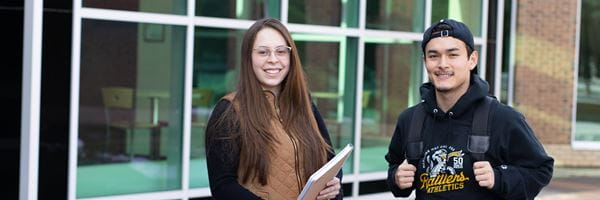 Two students standing outside main entrance