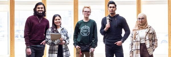 Five students standing in gathering space