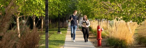 Two students walking on a sidewalk.