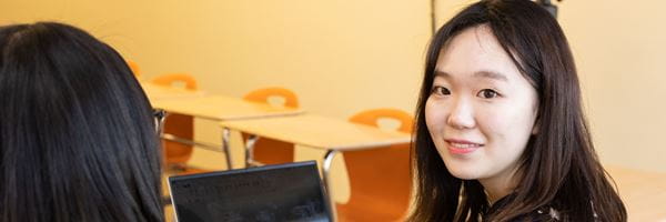 Student sitting in a classroom, smiling.