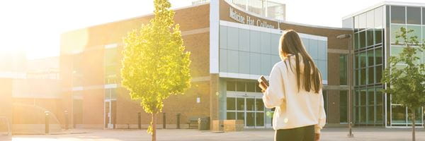 Student walking towards the college, sunset in the background