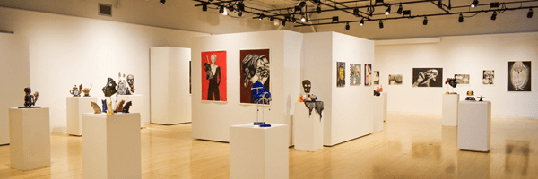 Wide shot of One on One Gallery space with artwork being displayed on walls and podium stands. 