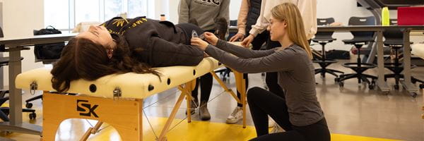 A group of students learning to use kinesiology tools in a functional anatomy class