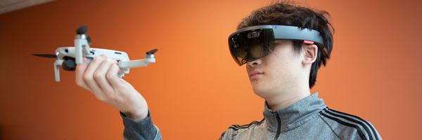 Student wearing VR goggles holding a drone
