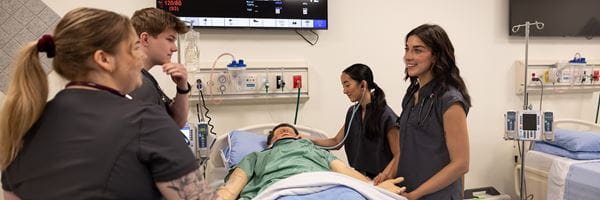 Four nursing students at bedside of a simulation patient.