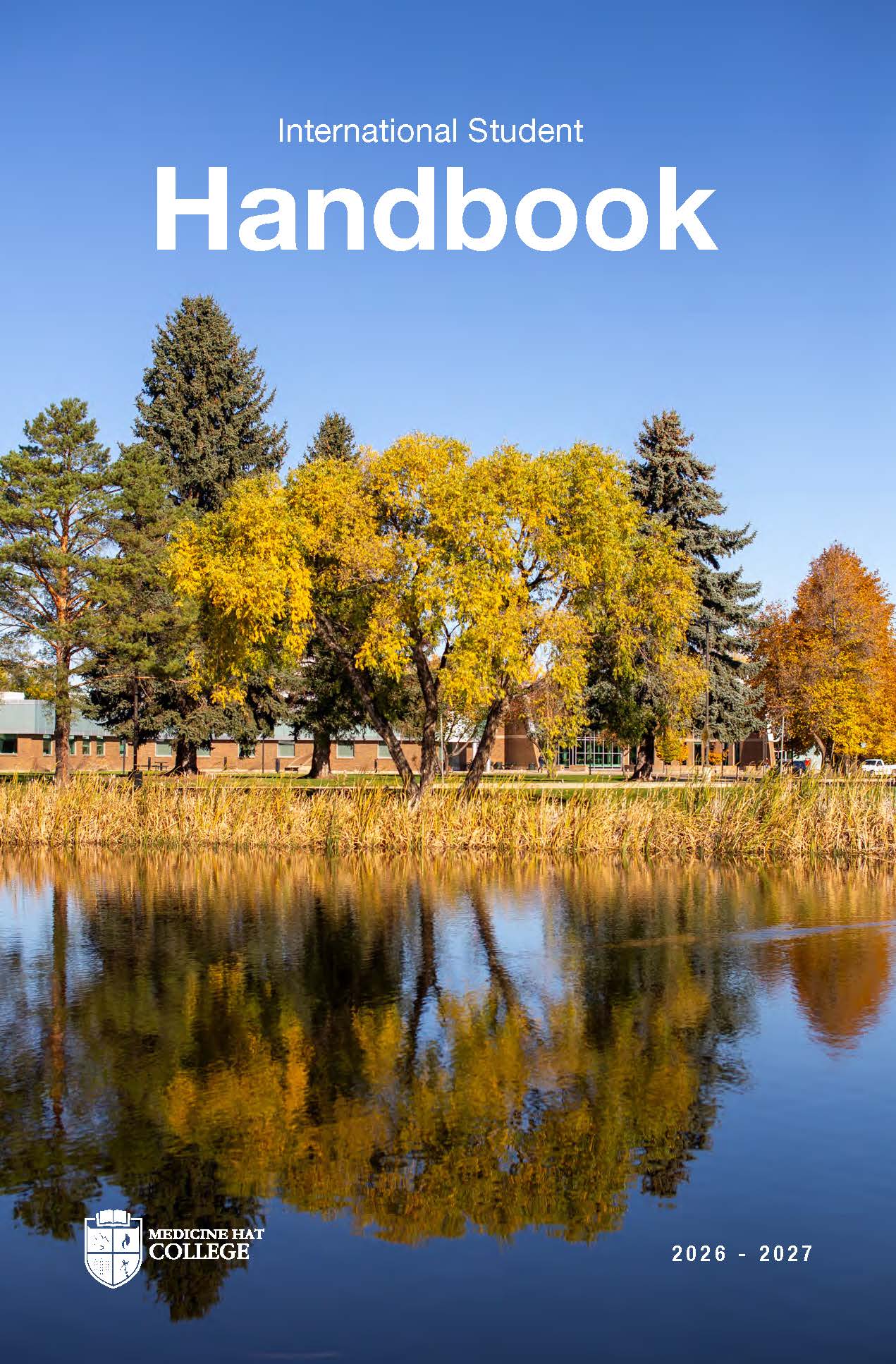 Front cover of the International Handbook. Behind the orange, green, and yellow leaves from a tree is the entrance the MHC campus with students walking among the grounds.