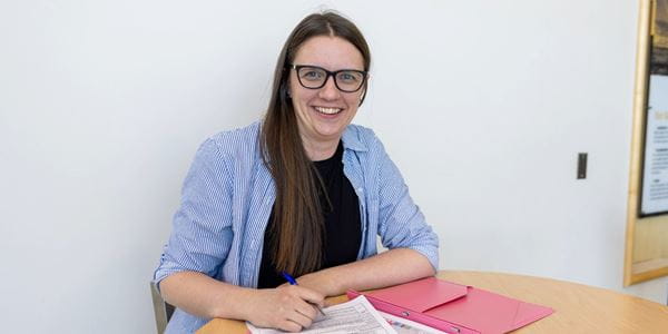 Ashley Reimer sitting at table in Centennial Hall with notebook. 