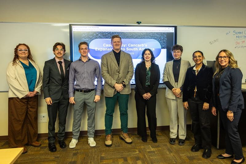 Seven MHC Business Administration students stand with Chris Sawicki for a photo at the Cancarb Case Competition