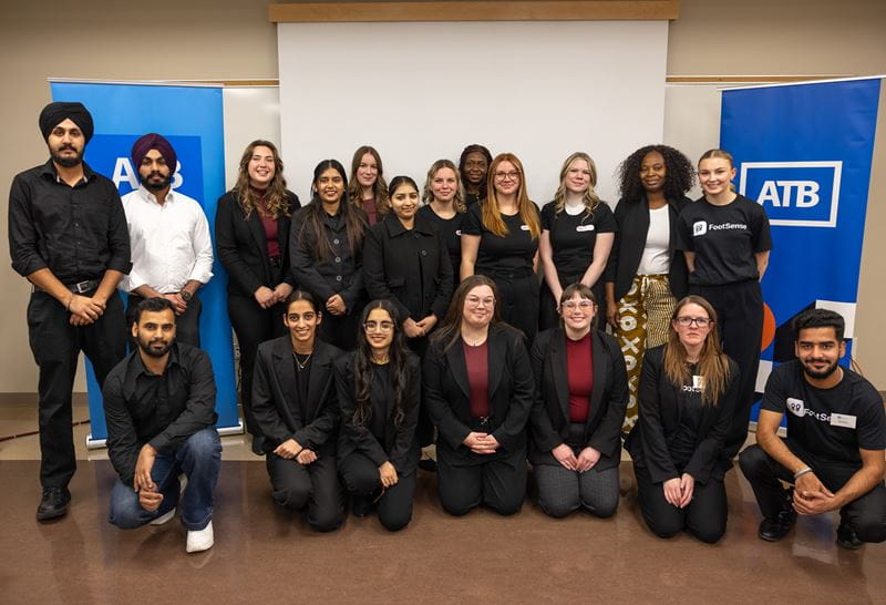 Nineteen students in the MHC School of Business pose for a photo in front of the ATB banner after taking part in Venture Design Studio