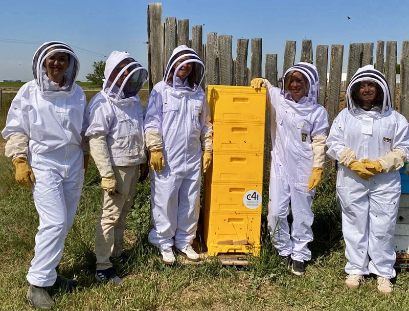 Five people in white beekeeper uniforms pose with their insulated hives used in research with MHC's Centre for Innovation (C4i)