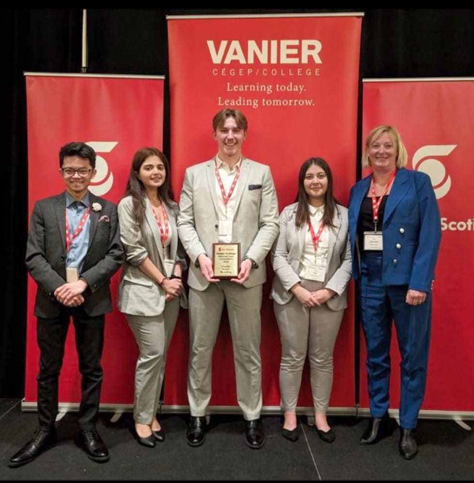 Four business students and instructor standing in front of Vanier College Case Challenge sign. 