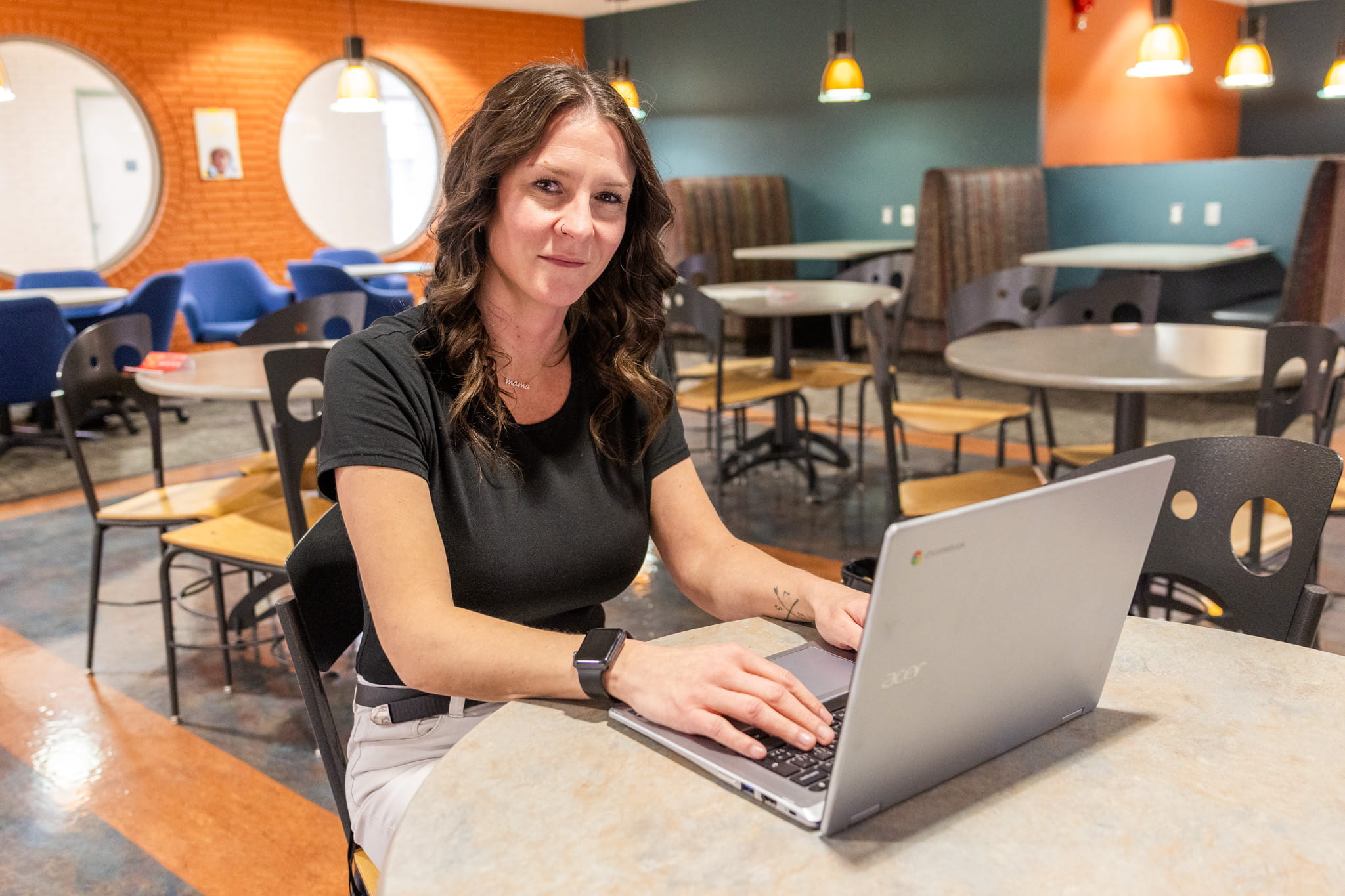 Jaime Loehndorf sitting at table in coffee shop with laptop.