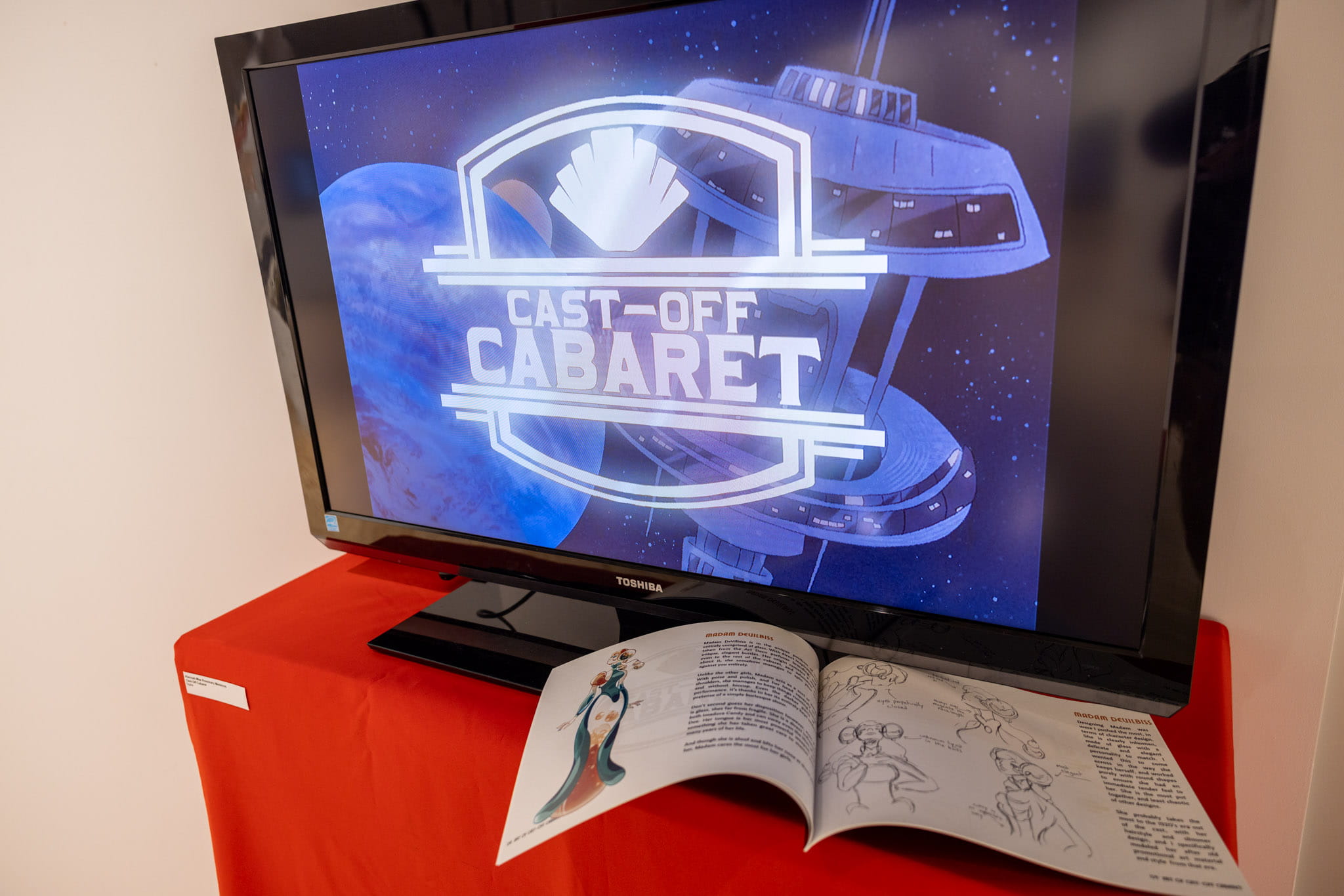 Alannah-Mae R Medeiros animation displayed on TV scene with a book displayed with her written process. 