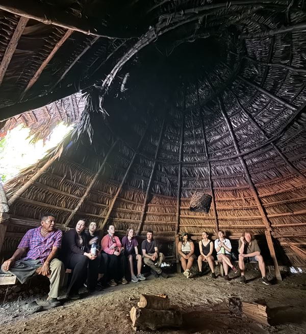 Students sitting in a circle in a BriBri hut.