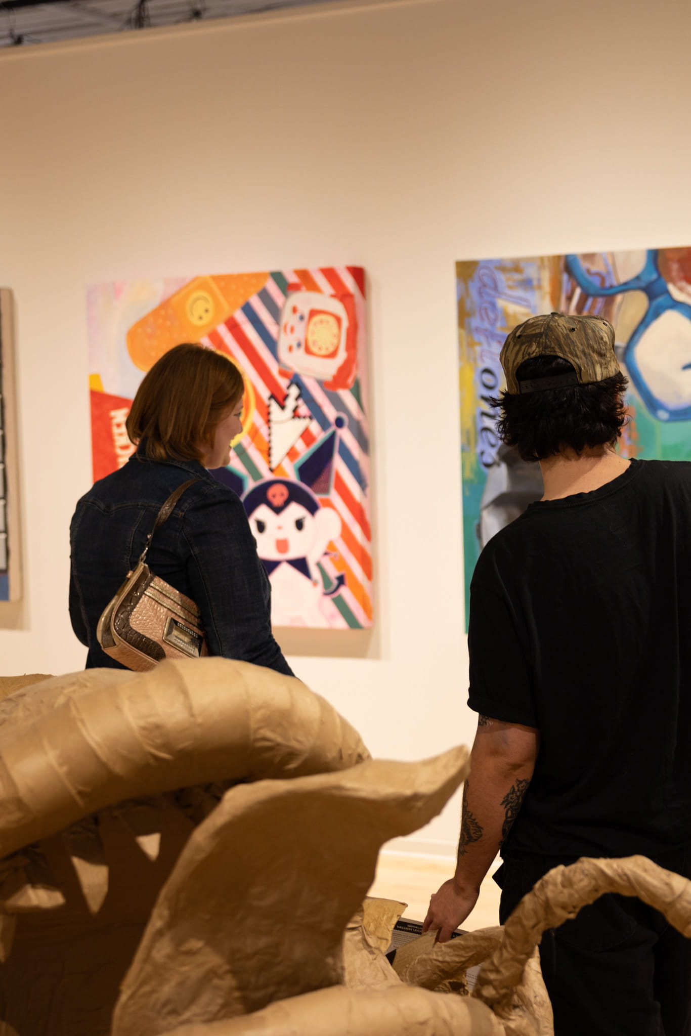 A man and a woman look at paintings.