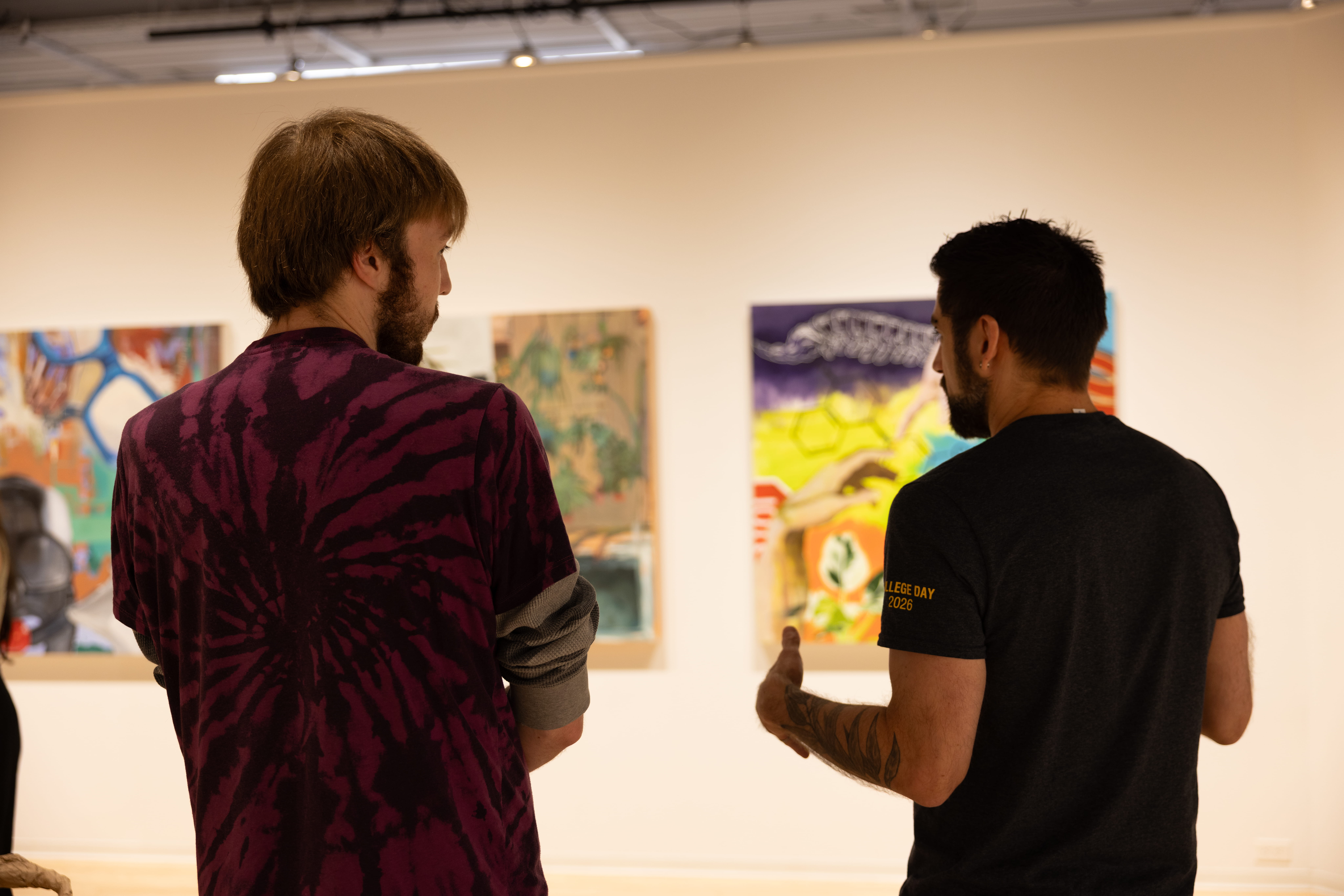 Two men look at several art pieces.