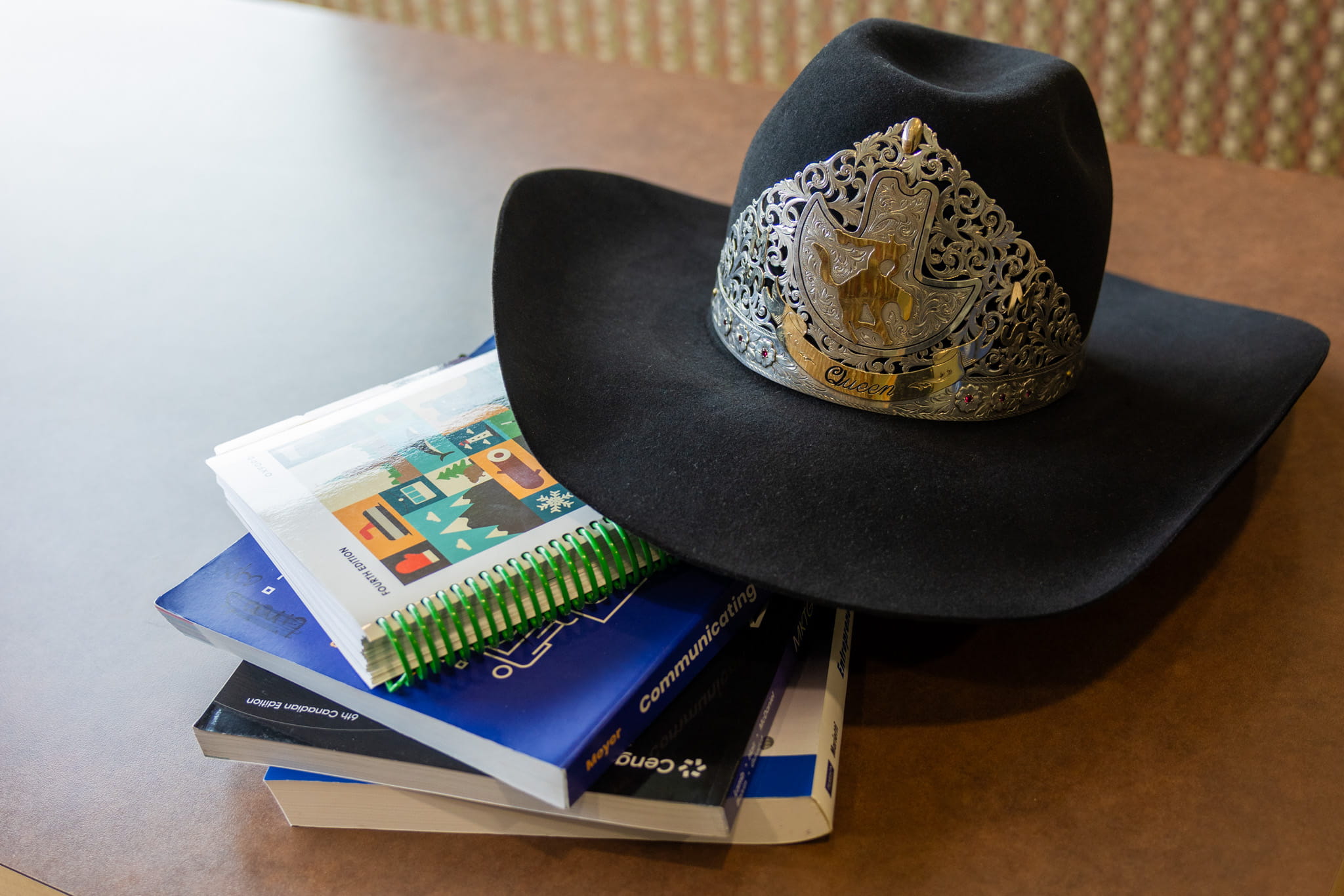 Cowboy hat with tiara on top of marketing textbooks.