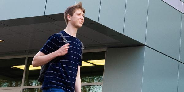 Student with backpack walking outside of library
