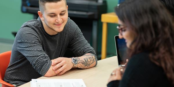 Two students sitting at a table looking at an assignment
