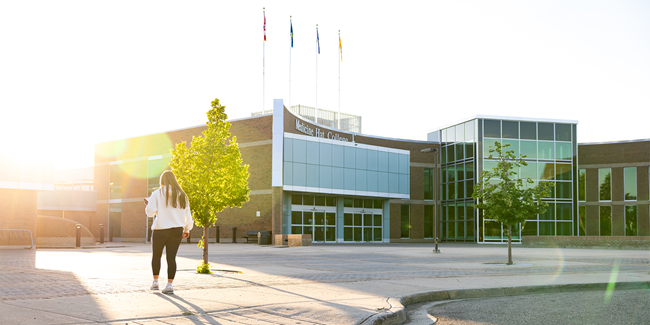 Student walking up to the front entrance of Medicine Hat College in the sunset