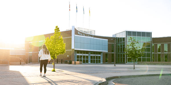 Student walking up to the front entrance of Medicine Hat College in the sunset